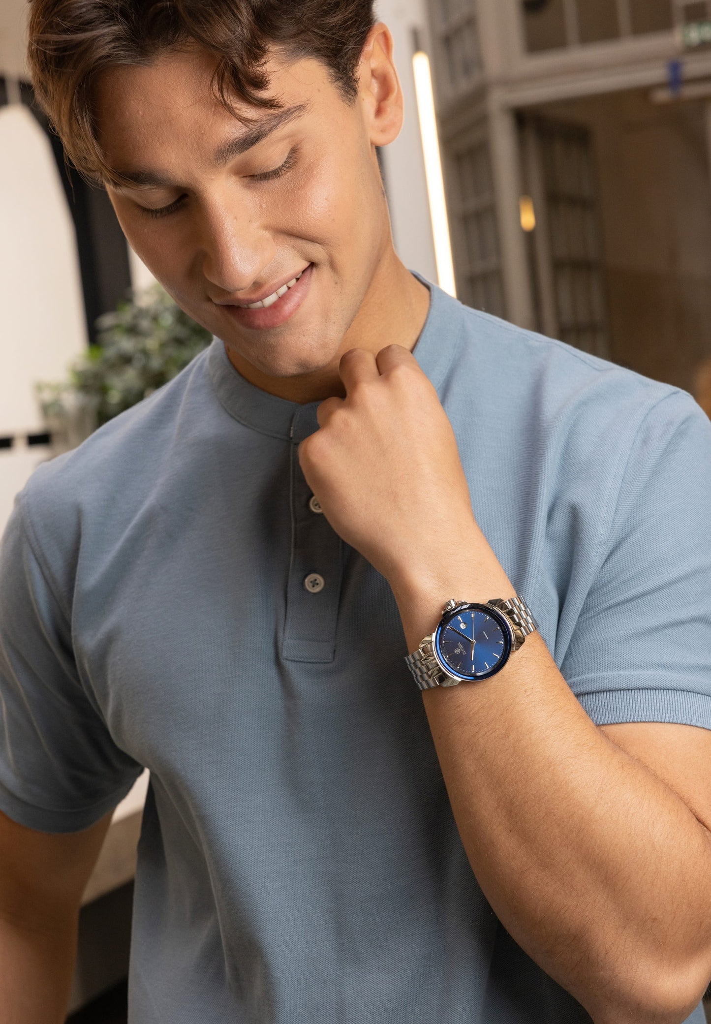 swiss made watch for men - worn by a man with blue t-shirt - with silver strap and blue dial - made in switzerland