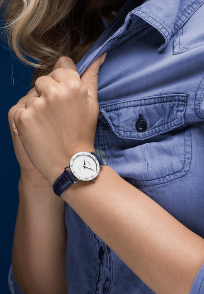 Blue swiss watch for women - with blue leather strap and white dial - worn by a women holding her shirt