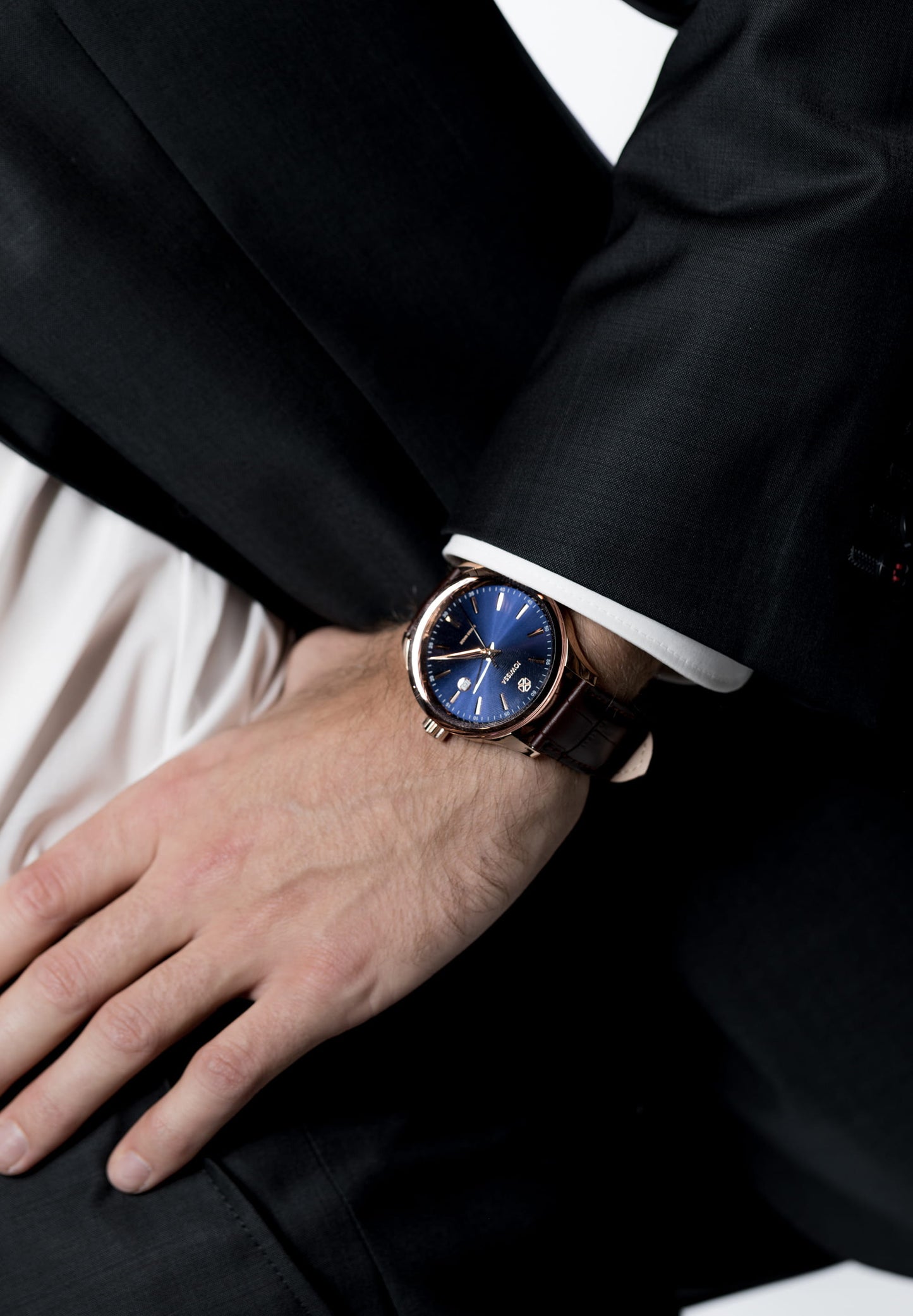 Detailed view of Tiro Watch J4.203.L highlighting the attractive rose-gold hour markers against the blue sunray dial - worn by a man in a black suit and white shirt