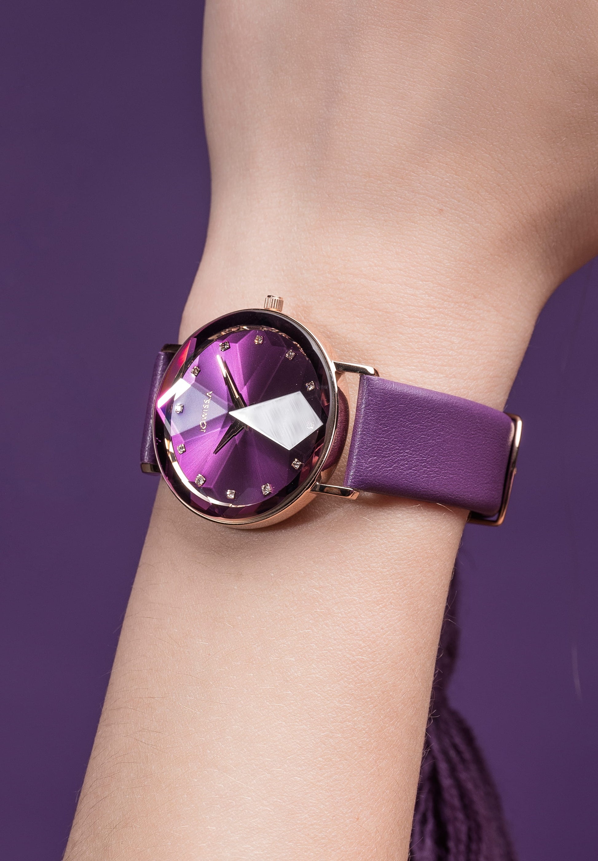 Purple swiss watch for women worn by a girl showing her hand - the watch has purple leather strap and gold details in the front - all swiss made